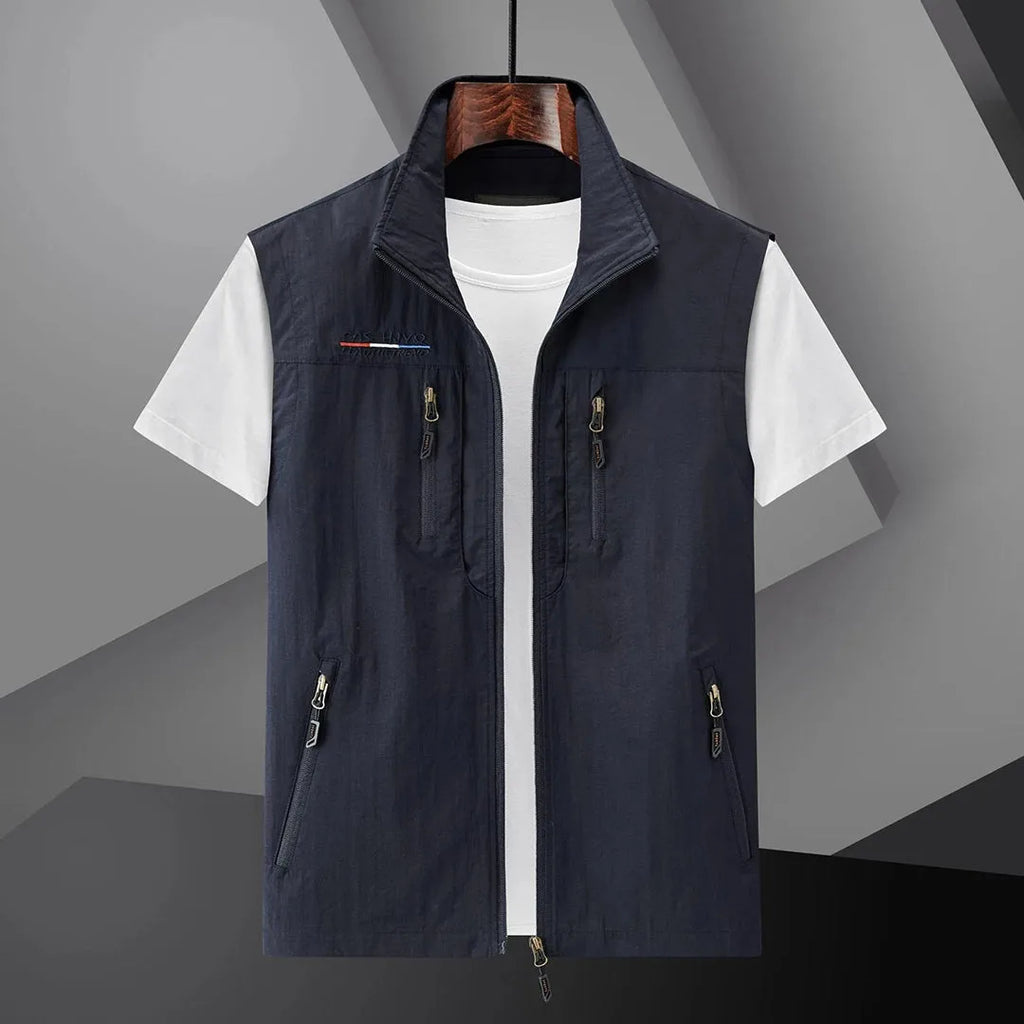 Navy sleeveless zip-up gilet with stand collar and chest zip pockets, displayed open over a white t-shirt