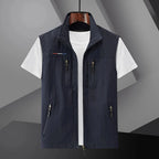 Navy sleeveless zip-up gilet with stand collar and chest zip pockets, displayed open over a white t-shirt
