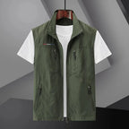 Olive green sleeveless zip-up gilet with front zip and four zip pockets, worn open over a white t-shirt
