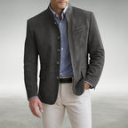 Man wearing a grey suede mandarin collar jacket over a striped shirt, buttoned front with flap pockets visible