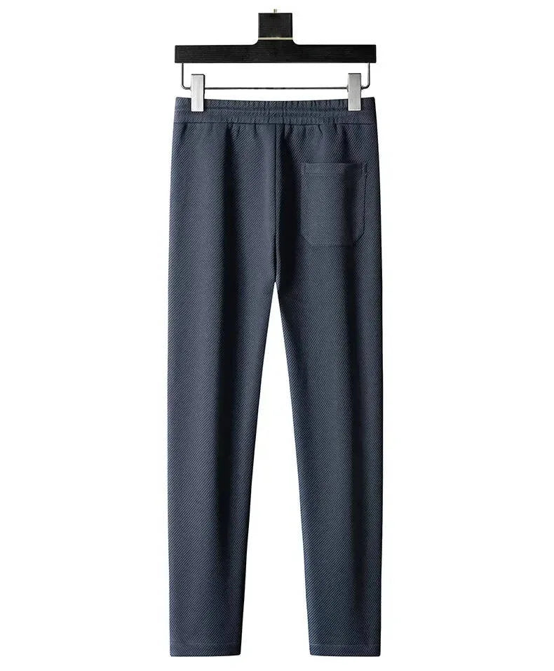Back view of grey textured tracksuit trousers showing patch pocket and elastic waistband
