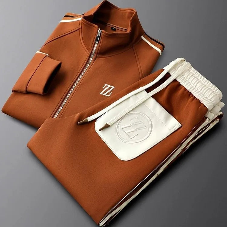 Folded chestnut brown zip-up jacket and joggers with cream drawstring waistband and embroidered logo pouch pocket