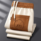 Close-up of the cream elasticated waistband and embroidered logo pocket on the brown joggers