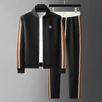 Black zip-up jacket and joggers on hangers with tan and white side stripes, worn over a white t-shirt