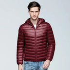 Front view of a man wearing a wine red quilted puffer jacket with stand-up hood, zipped to the neck