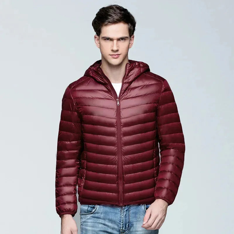 Front view of a man wearing a wine red quilted puffer jacket with stand-up hood, zipped to the neck