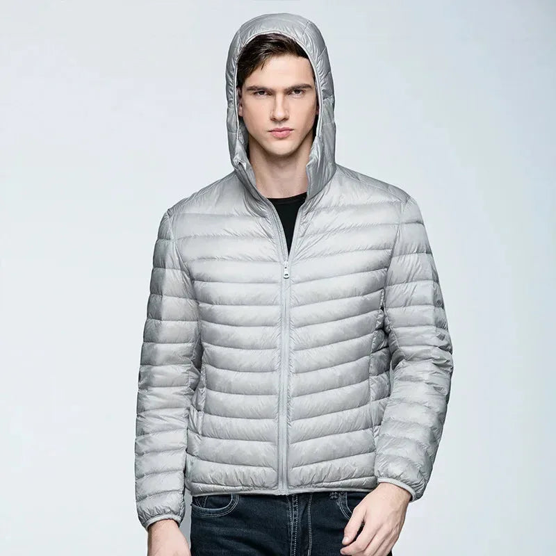 Front view of a man wearing a light grey puffer jacket with the hood pulled over his head