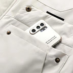 Close-up of the lower chest pocket with press studs holding a smartphone, showing bronze hardware