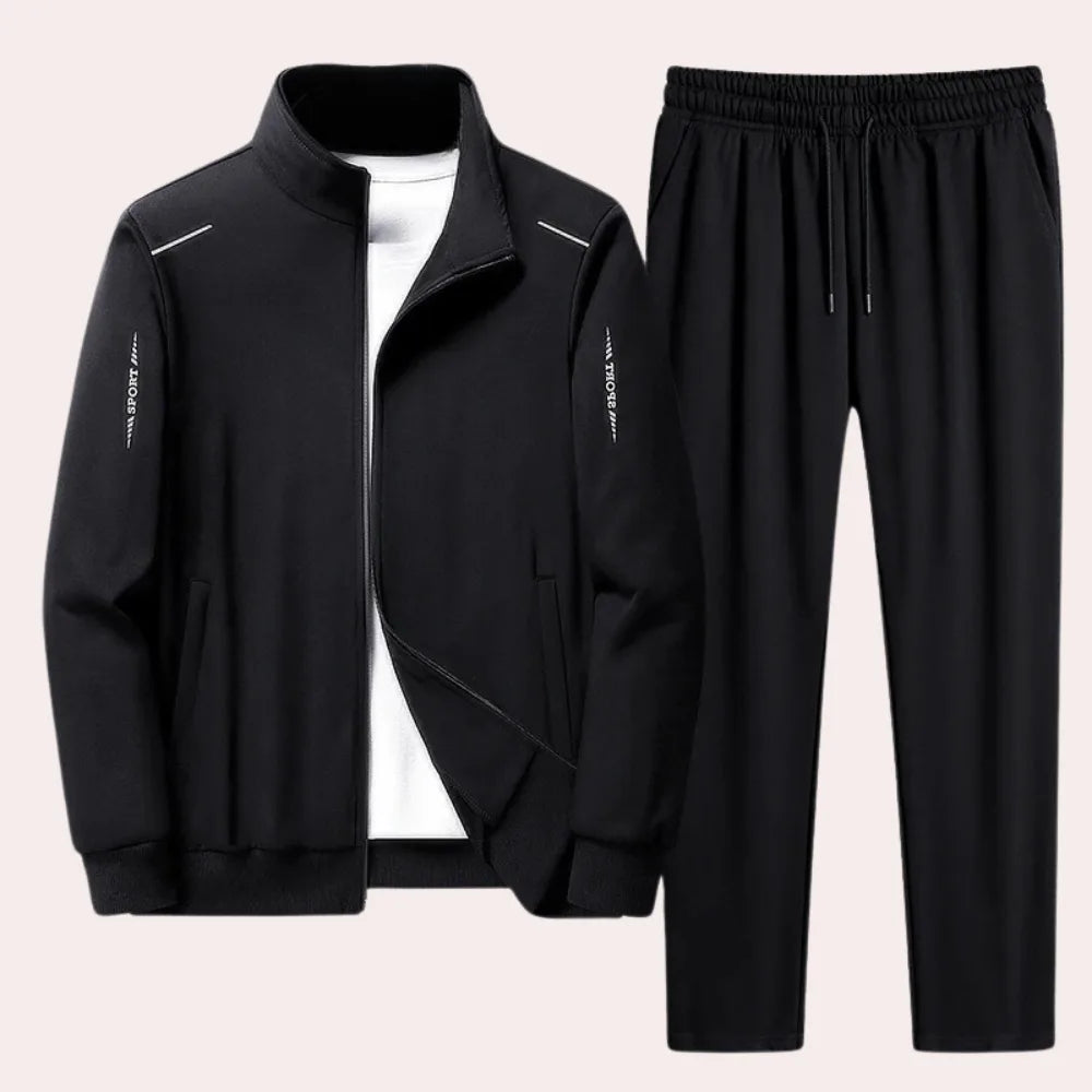 Black full-zip tracksuit jacket with stand-up collar layered over a white t-shirt, shown with matching black joggers