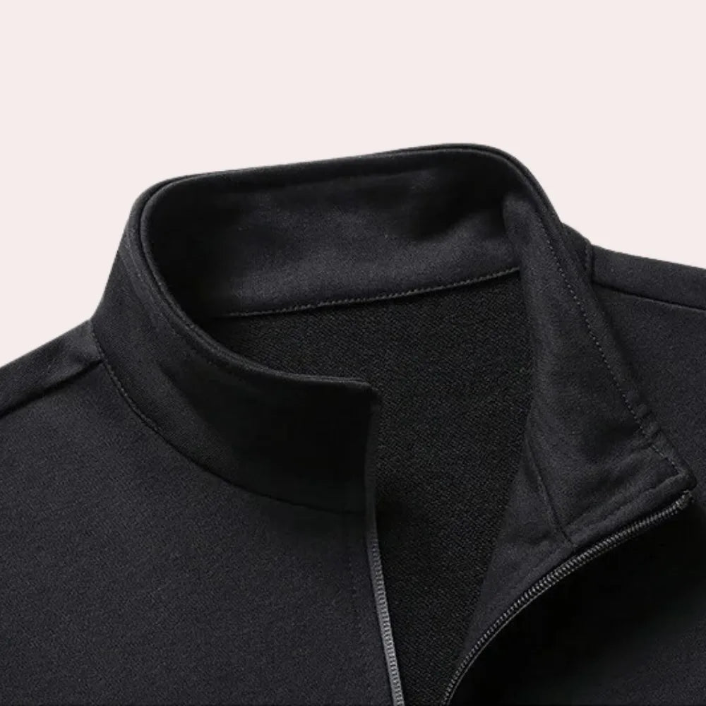Close-up of the stand-up collar and zip detail on the black tracksuit jacket, showing the fabric texture