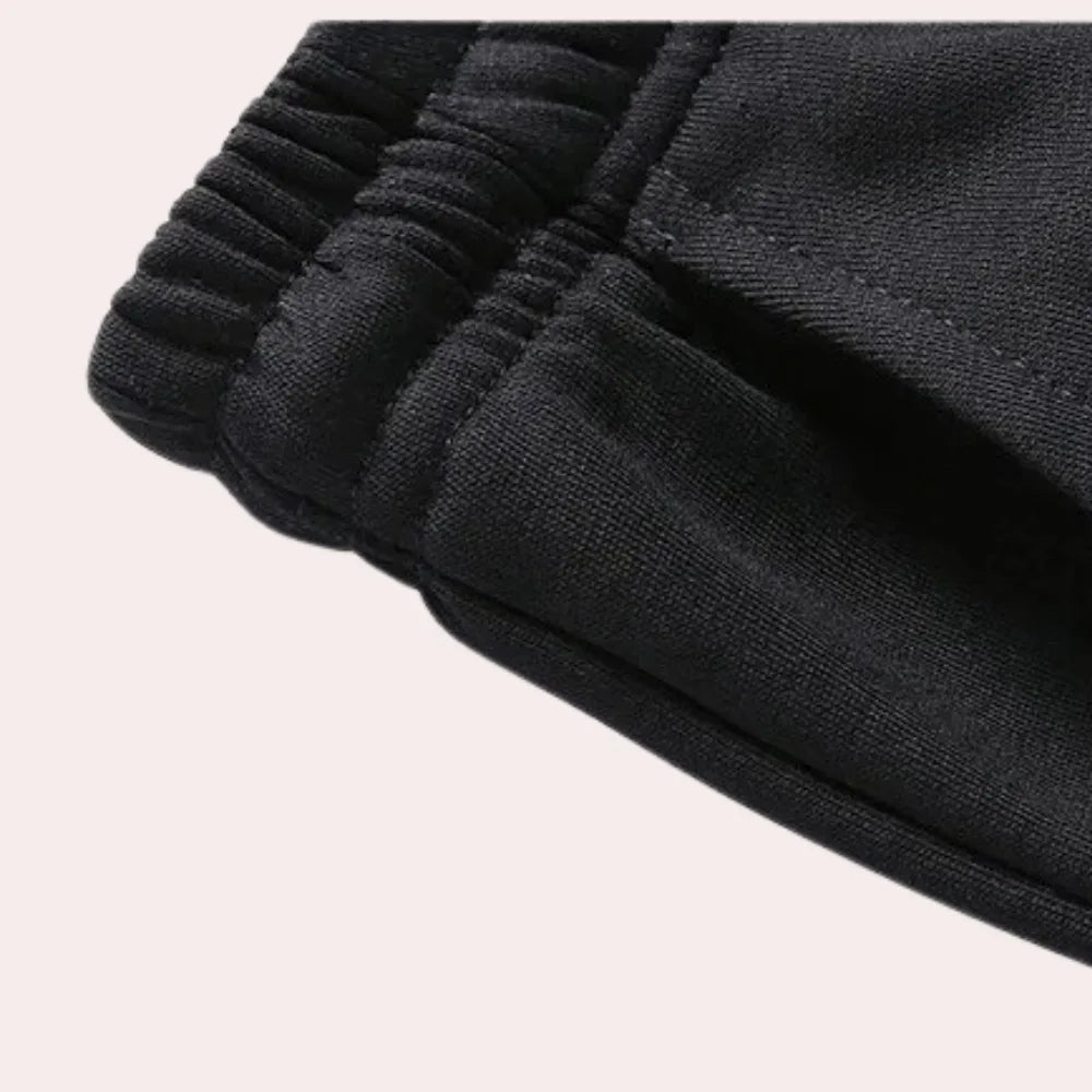 Close-up of the elasticated waistband and drawstring on the black joggers, showing the ribbed stitching
