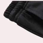 Close-up of the elasticated waistband and drawstring on the black joggers, showing the ribbed stitching