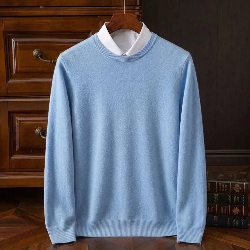 Pale sky blue crew neck jumper with ribbed trim, layered over a crisp white shirt collar on a wooden hanger