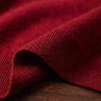 Close-up of the deep red knit fabric folded to show its fine ribbed texture and soft fibres