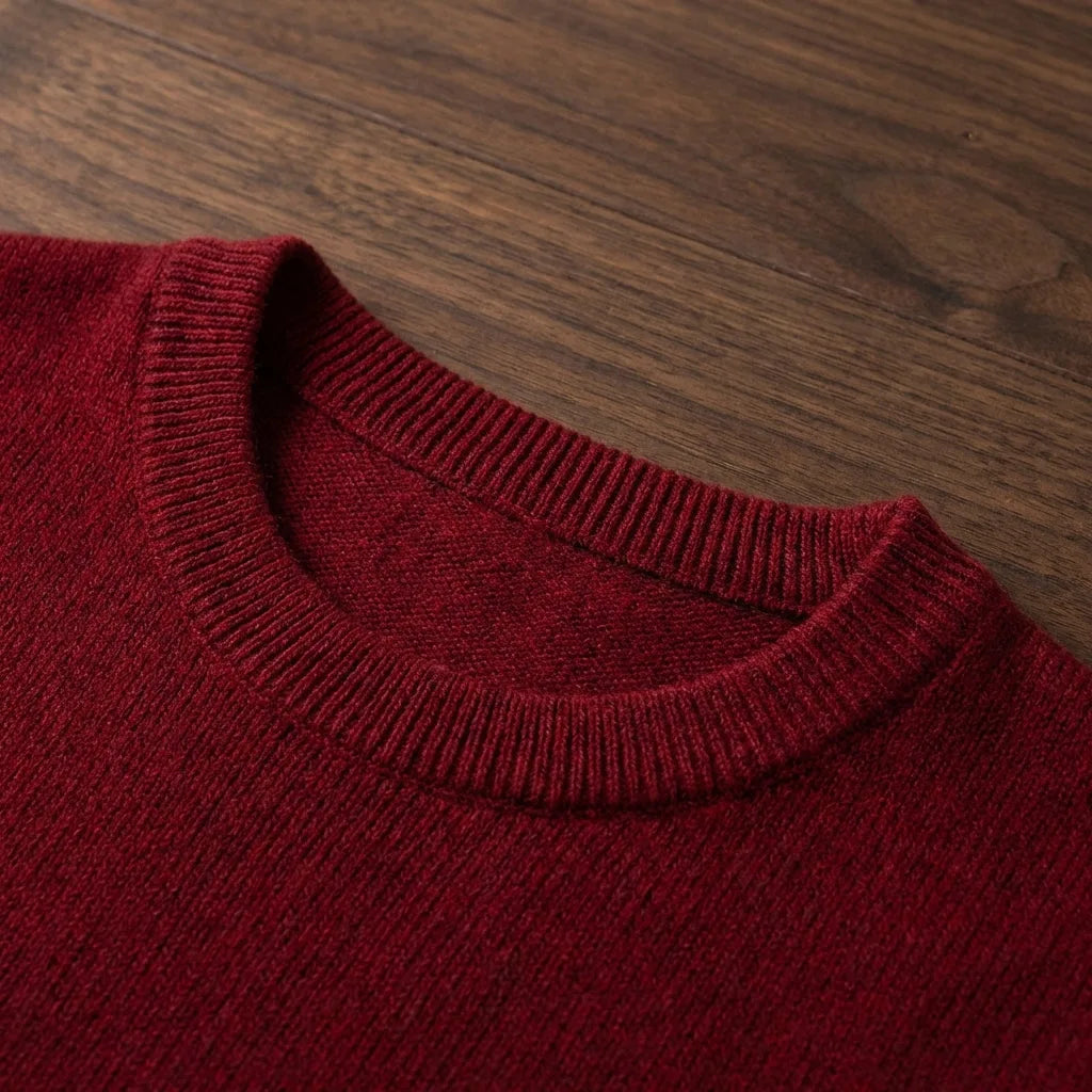 Front view of a red crew neck jumper worn over a white shirt, set against carved wooden drawers and a parquet floor