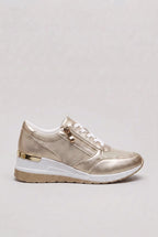 Side view of gold metallic wedge trainer with white laces, gold side zip and gold heel trim on hidden wedge sole