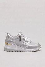 Side view of silver metallic wedge trainer with white laces, side zip and gold heel trim on a white wedge sole