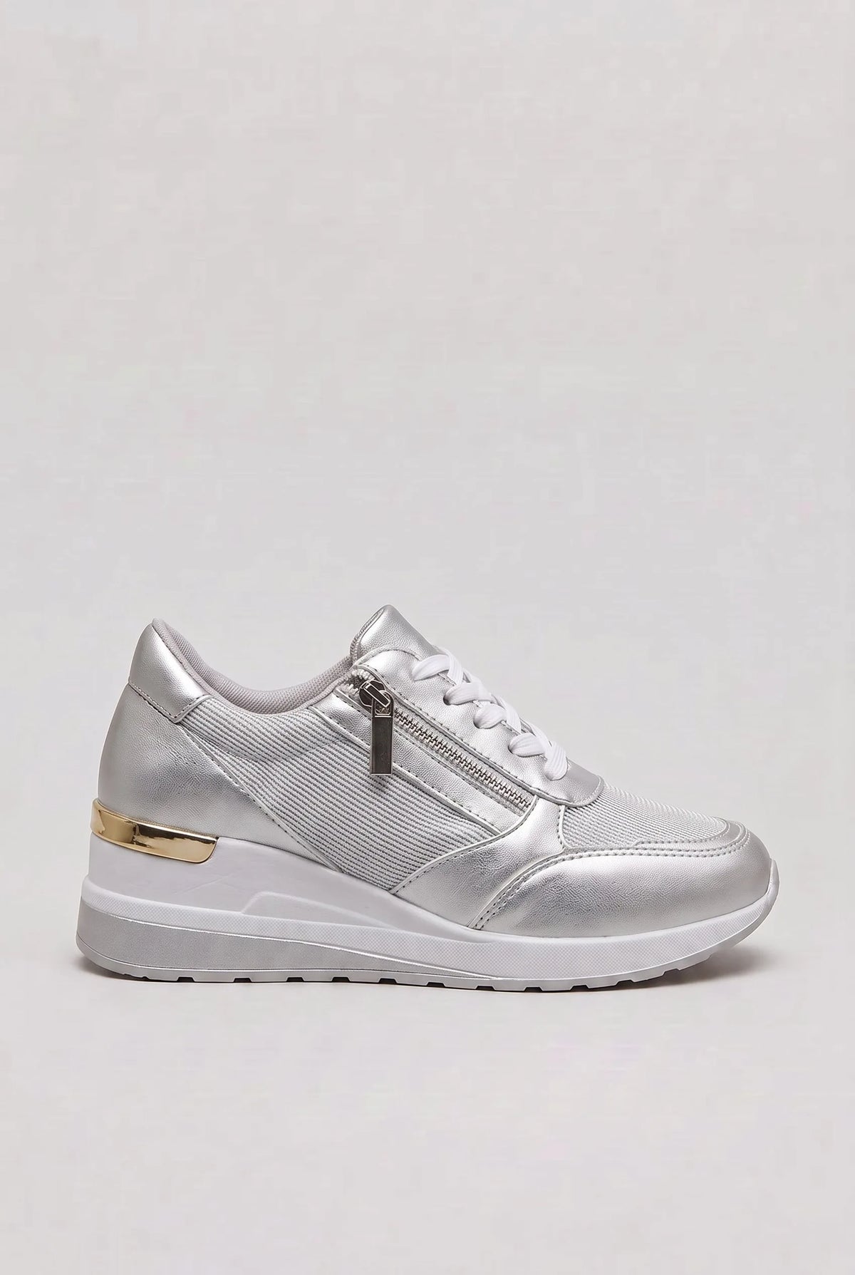 Side view of silver metallic wedge trainer with white laces, side zip and gold heel trim on a white wedge sole