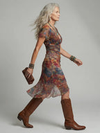 Side profile walking shot showing the flowing asymmetrical hem, side slit and flutter sleeve of the printed mesh midi dress
