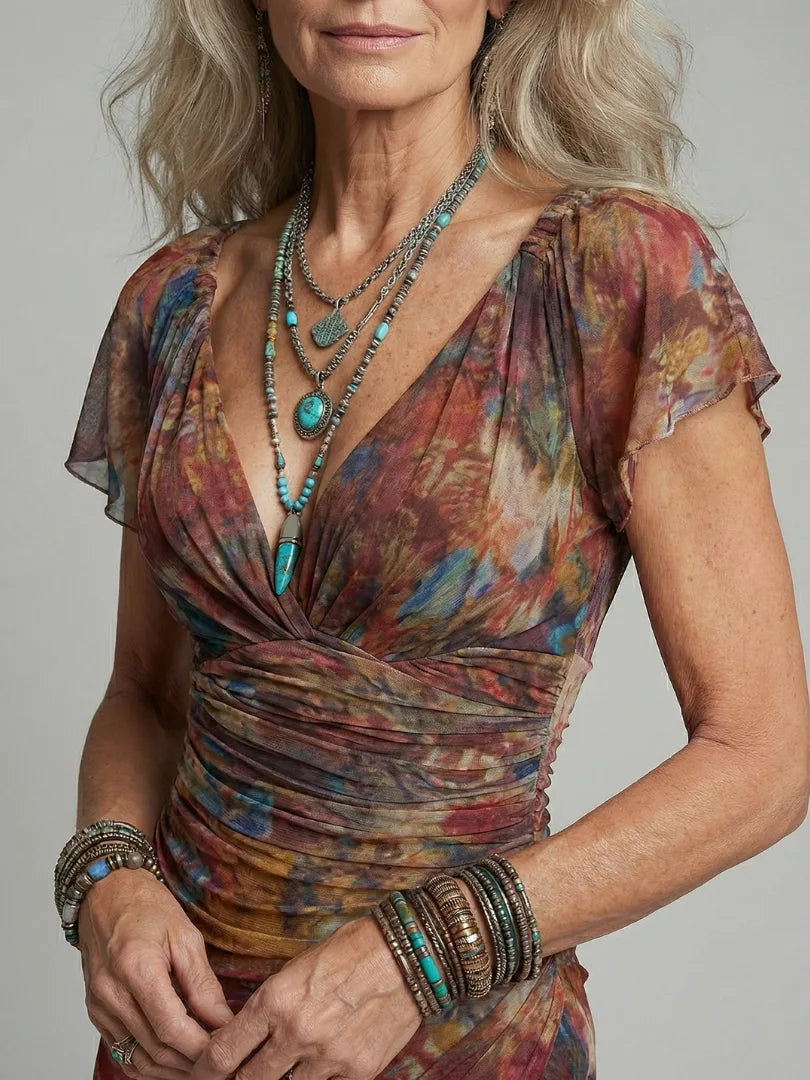Close-up of the plunging v-neckline, ruched bodice and multicolour print detail with layered turquoise and silver jewellery