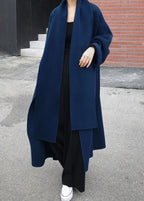 Model wearing the navy wool-look coat open over an all-black outfit, showing dropped shoulders and long scarf lapel