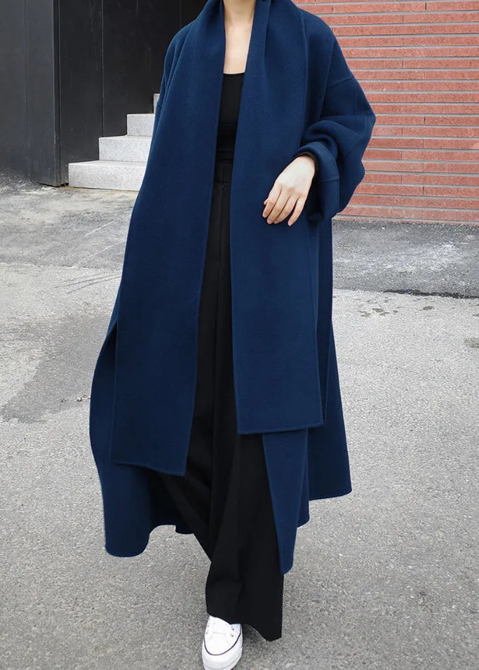 Model wearing the navy wool-look coat open over an all-black outfit, showing dropped shoulders and long scarf lapel