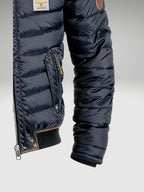 Close-up of side welt pocket with press stud and quilted sleeve detail on the navy puffer jacket