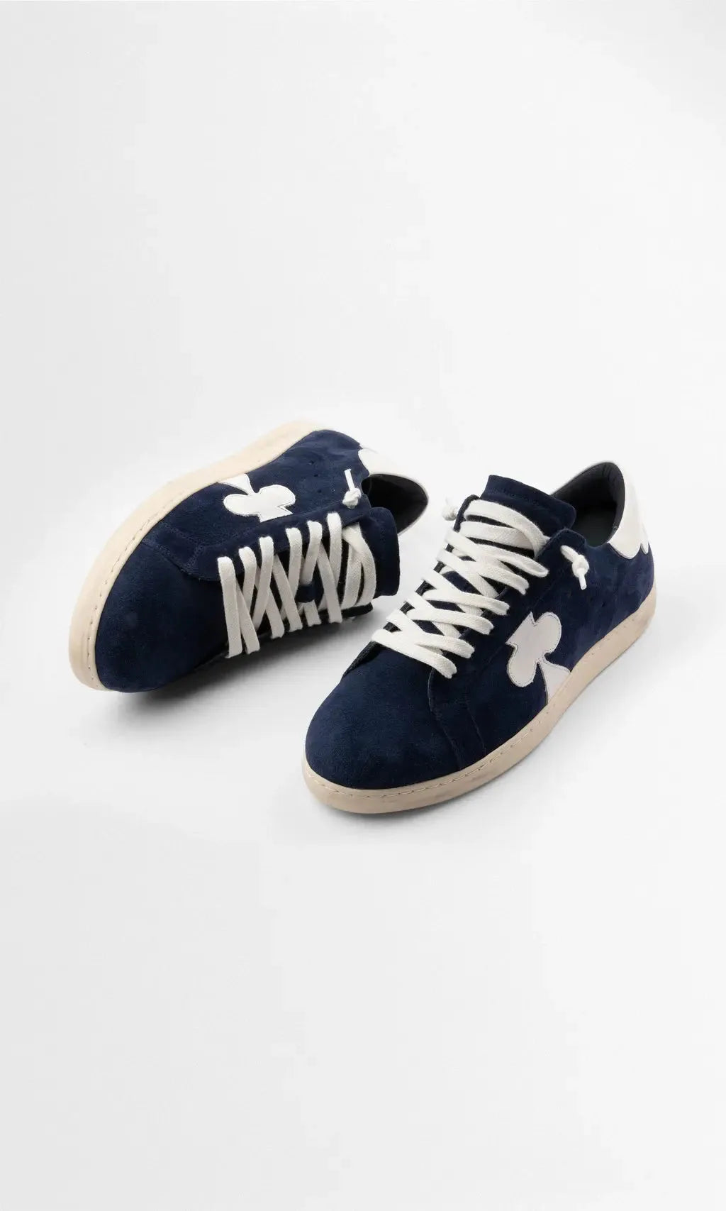 Overhead angled view of both trainers showing the padded tongue, white laces and textured suede upper