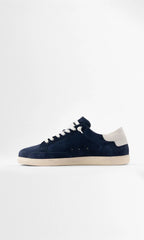 Full side view of the navy suede trainer showing the white heel panel with embossed branding and stitched sole detail