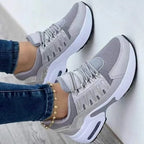 Grey chunky trainers with mesh panels and white air-cushion sole, worn with skinny jeans and a gold anklet