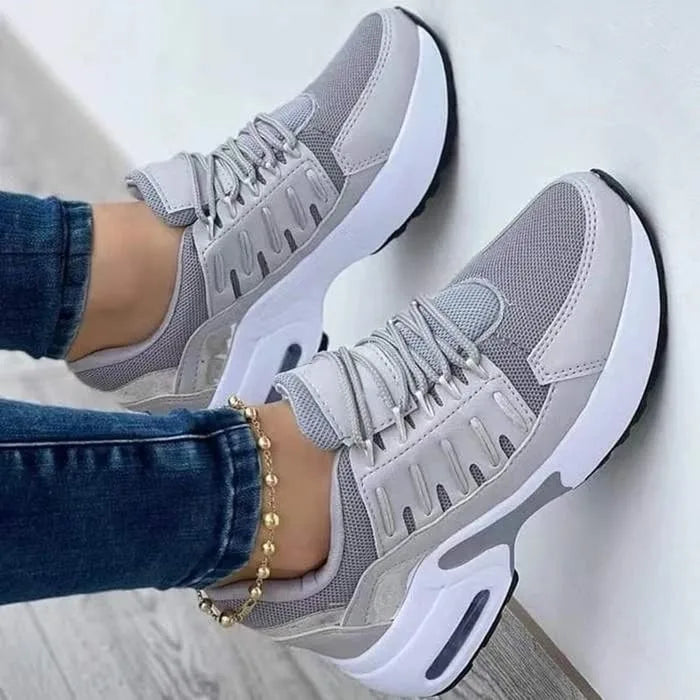 Grey chunky trainers with mesh panels and white air-cushion sole, worn with skinny jeans and a gold anklet