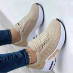 Beige and gold chunky trainers with lace-up front and white platform sole, shown on model's feet