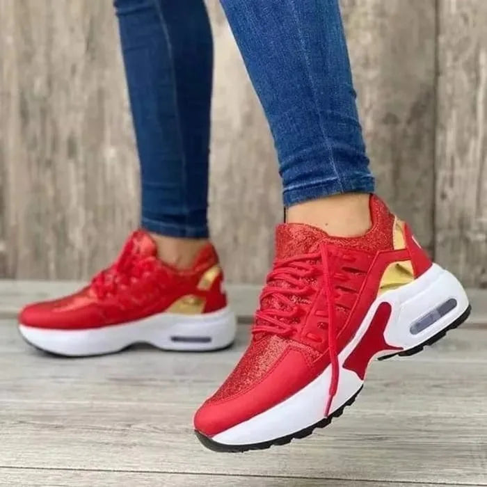 Red glitter trainers with gold accent panel and white platform midsole, worn with denim jeans