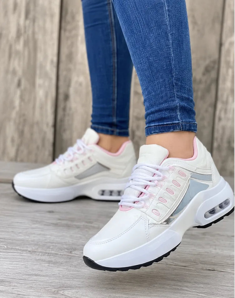 White trainers with pink trim and silver reflective panels, chunky white air-cushion sole, side view