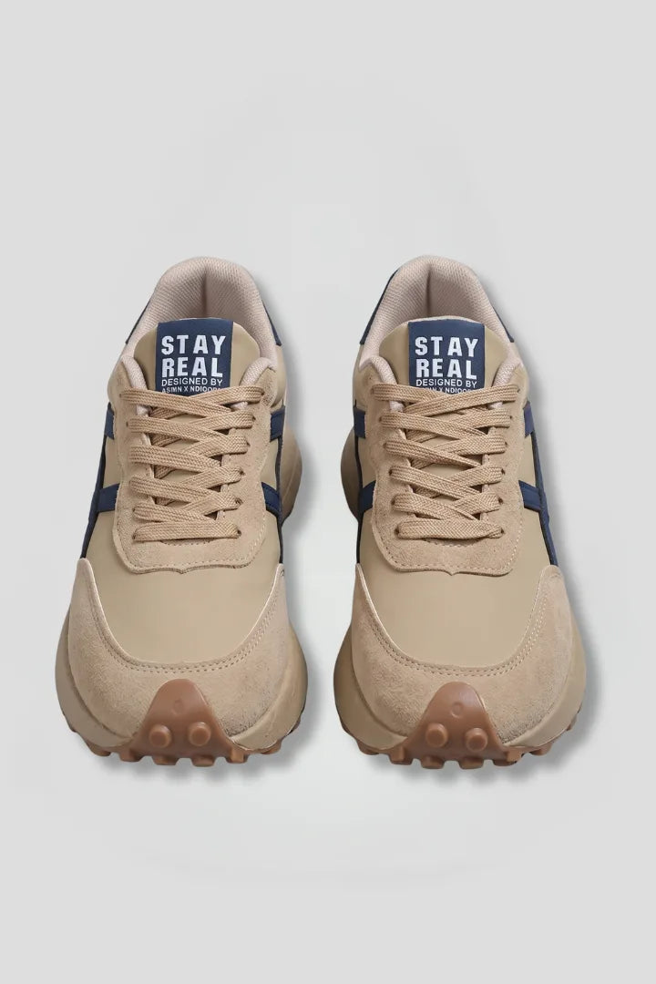 Top-down view of beige lace-up trainers with navy side panel stripe and gum-studded outsole