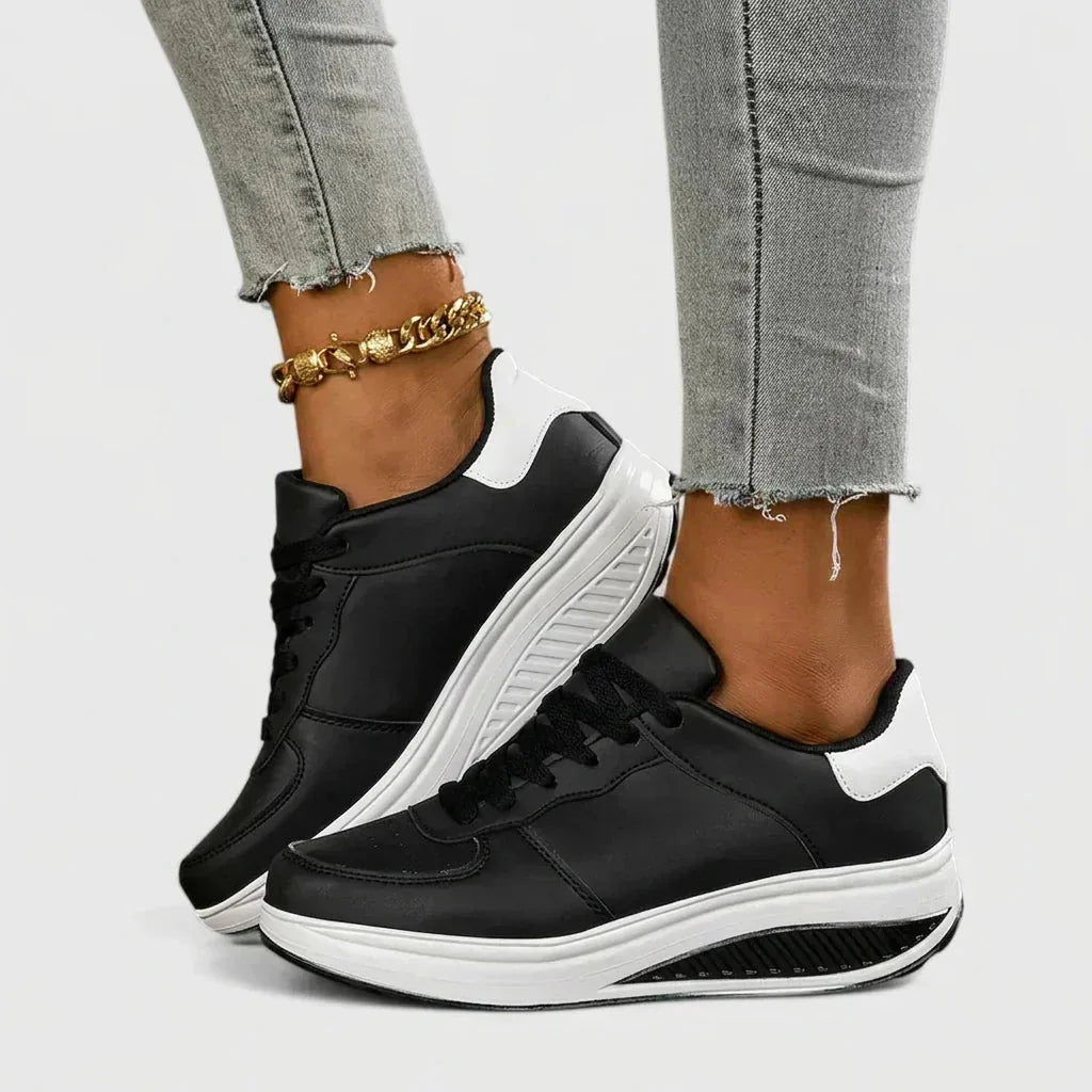 Front-angled view of black and white trainers highlighting the white contrast heel and ridged sole