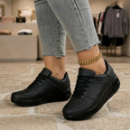Woman walking in black lace-up trainers with platform wedge sole inside a boutique setting
