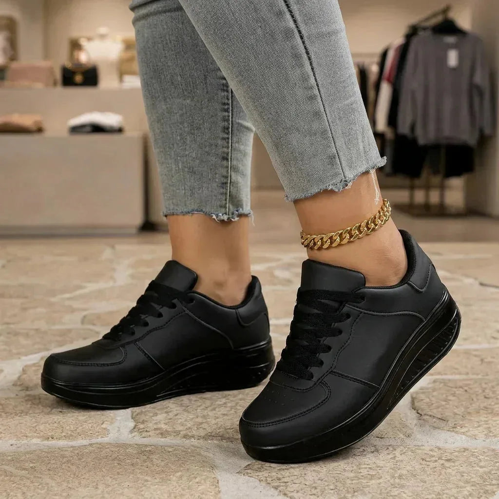 Woman walking in black lace-up trainers with platform wedge sole inside a boutique setting