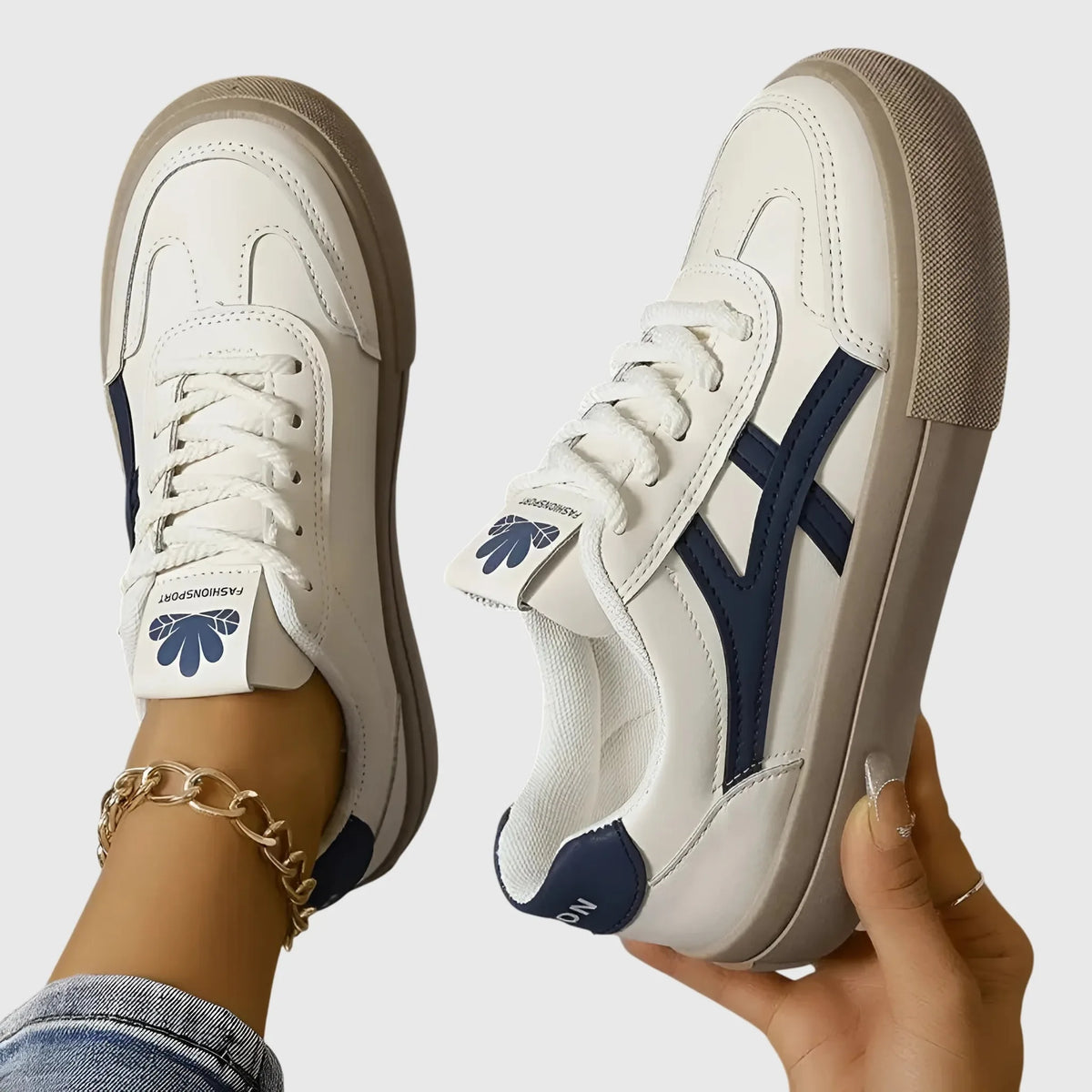 Side profile of a white leather trainer with navy stripe detail and thick beige sole, worn on foot