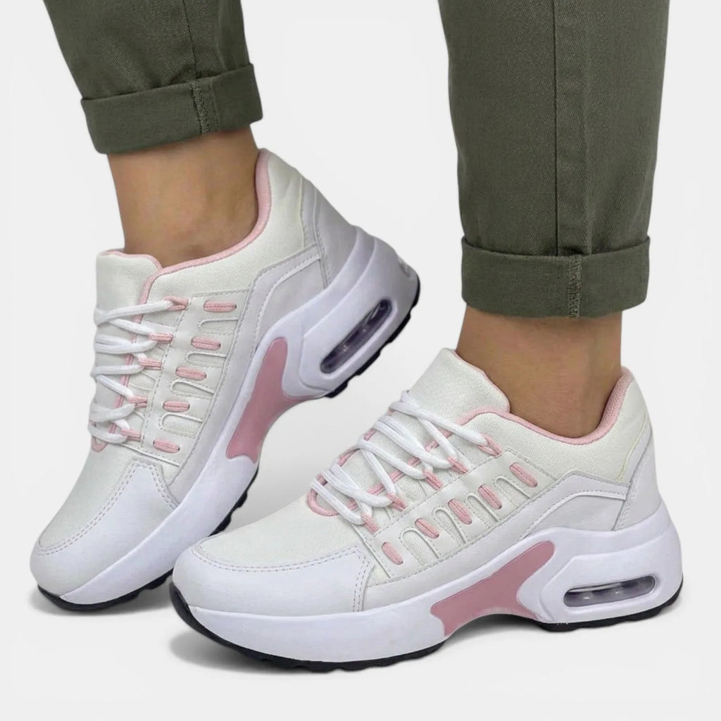 Side view of white and pink chunky trainers with visible air-cushioned sole, worn with rolled-up khaki trousers