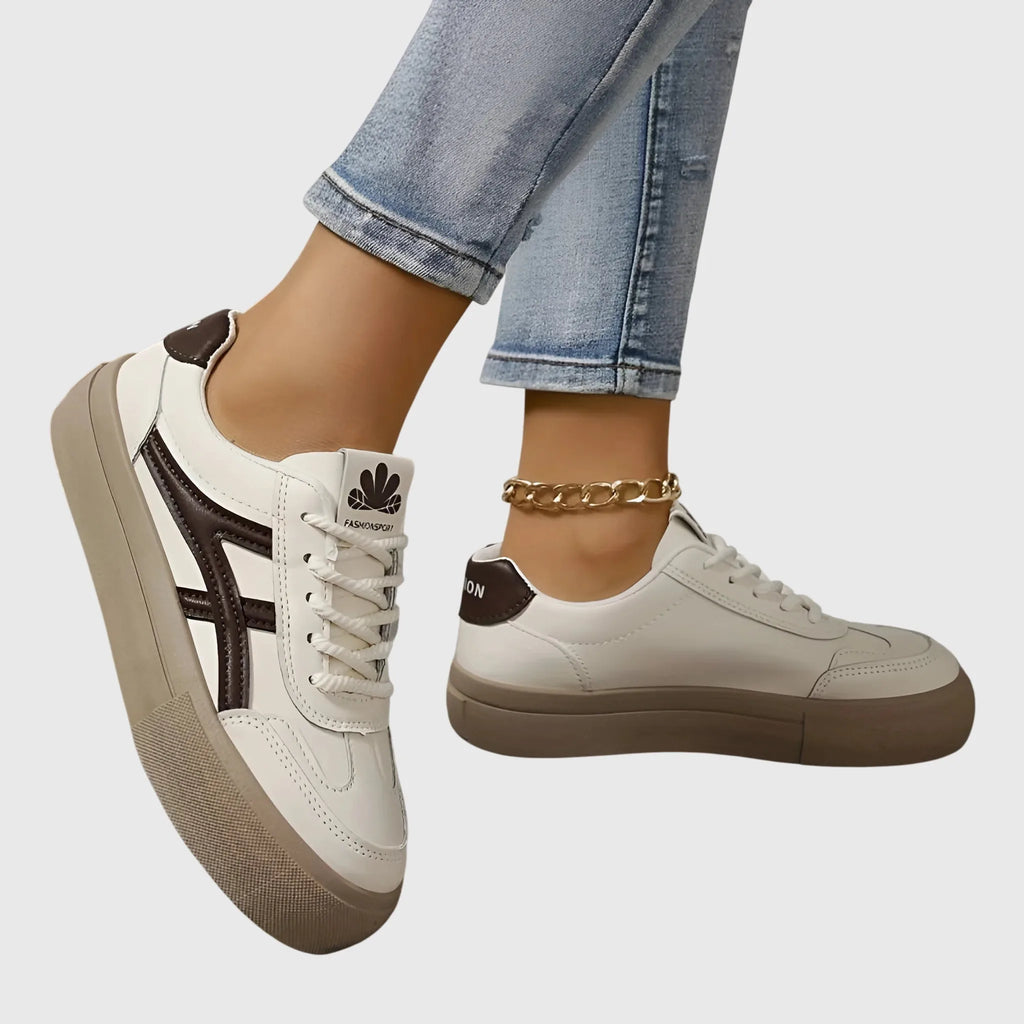 Angled view of white trainer with bold navy stripe across the side and textured beige toe cap