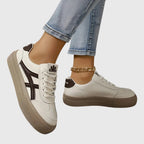 Angled view of white trainer with bold navy stripe across the side and textured beige toe cap
