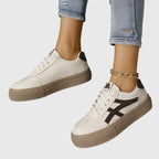 Front and back view of white trainer with brown stripe and brown heel tab worn with cuffed jeans