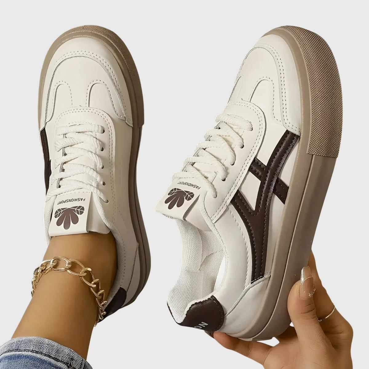 Two white trainers with navy stripe and beige sole held up and worn, showing sole tread and lining