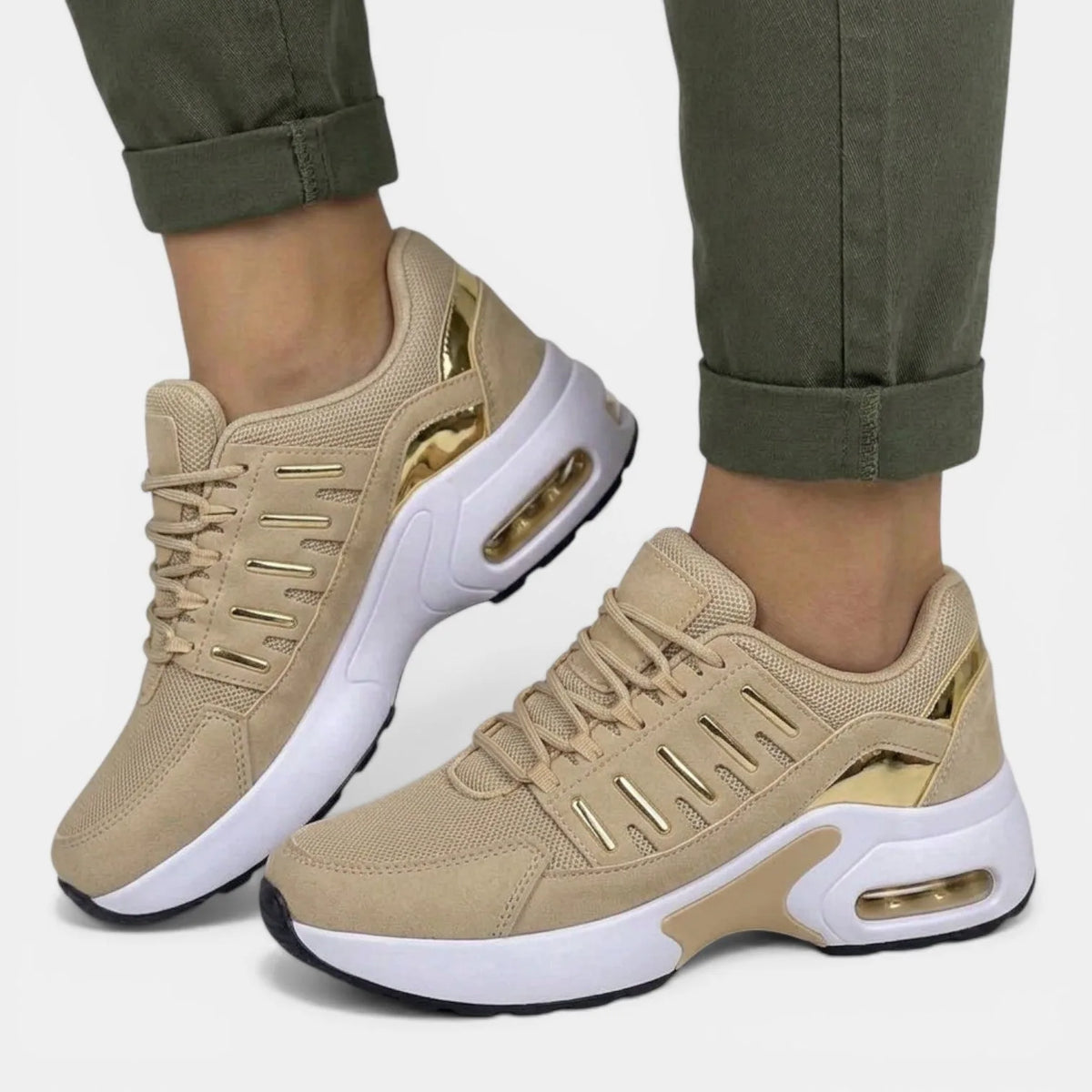 Side angle of beige suede-look trainers with metallic gold panel accents and white sole