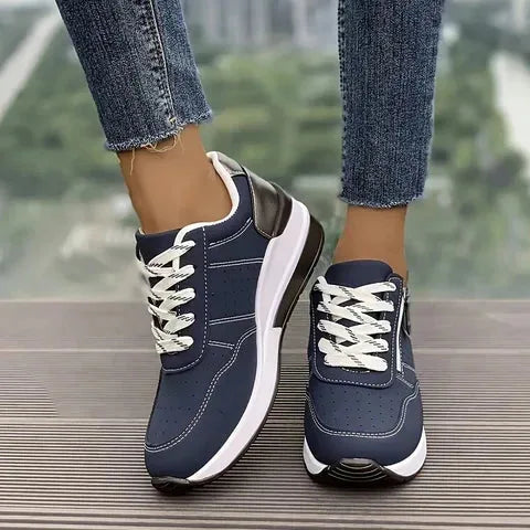 Close-up side profile of navy trainers showing contrast stitching, side zip and chunky white platform sole