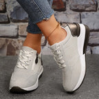 Front-angled view of black trainers with white laces and thick white platform sole worn with an anklet