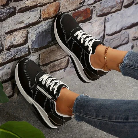 Side view of light grey trainers with dark bronze heel counter and perforated toe detail