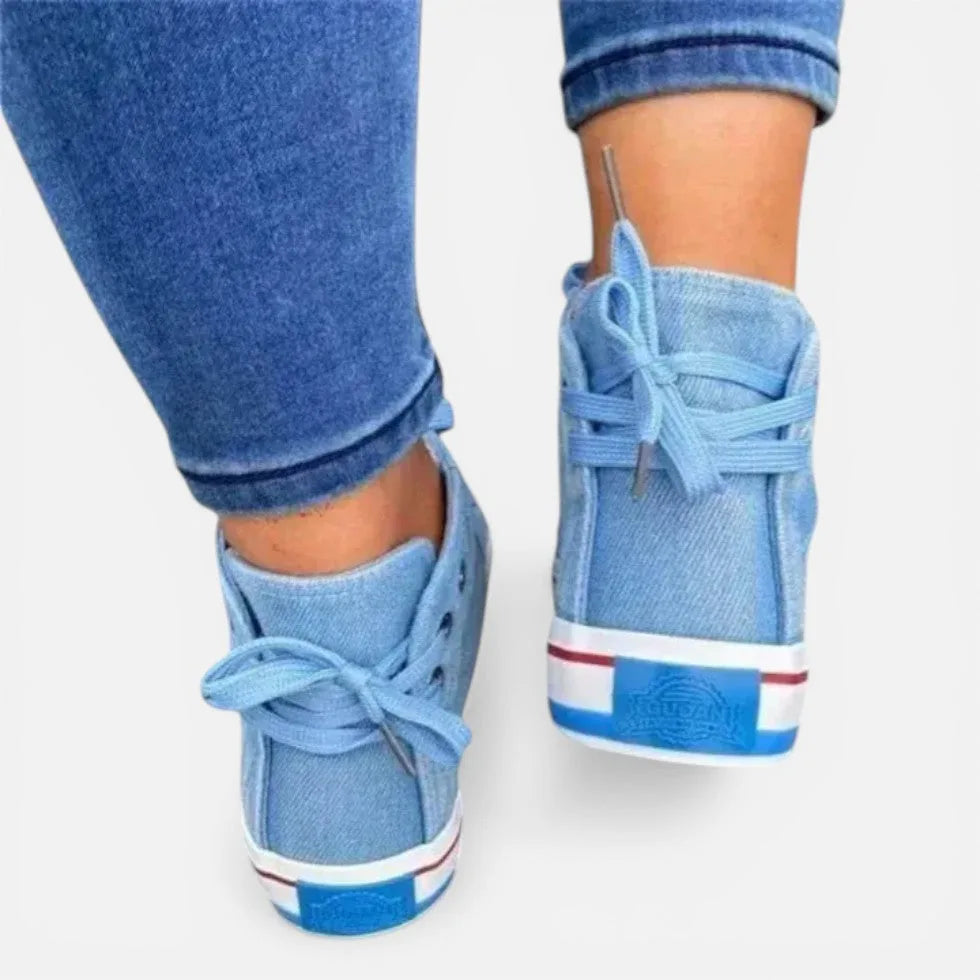 Back view of light blue denim high-top trainers showing heel pull tabs and red and white striped sole trim