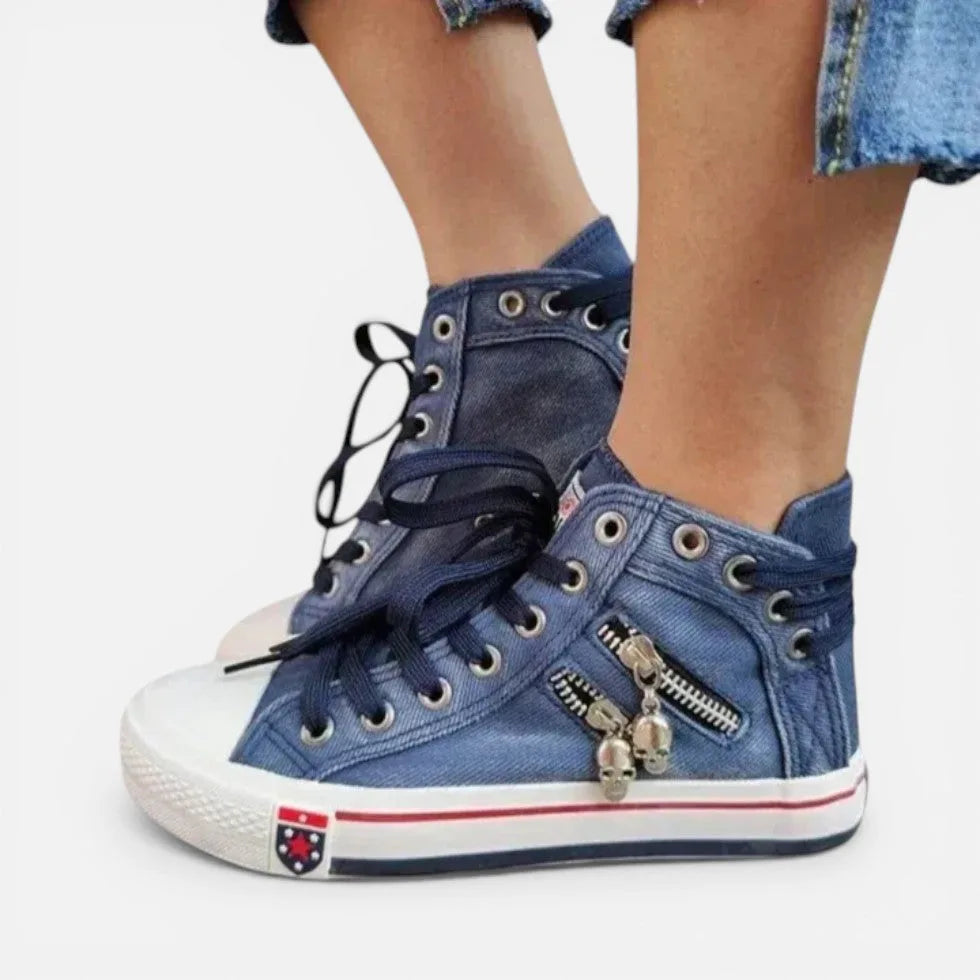 Close-up side profile of navy denim high-top trainers with dark laces, white toe cap and contrast striped sole